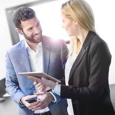 Man and woman are discussing in an office with people sitting on a desk