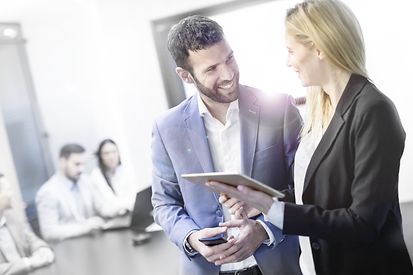 Un homme et une femme discutent dans un bureau avec des gens assis autour 