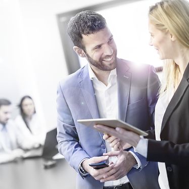 Man and woman are discussing in an office with people sitting on a desk